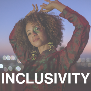 Woman standing on a rooftop wearing colorful makeup; text reads "Inclusivity"